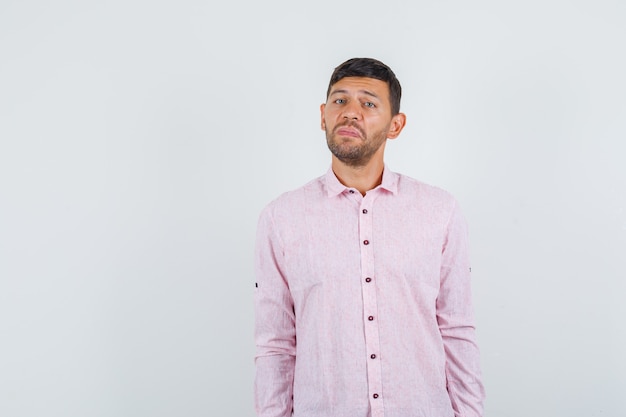 Young male in pink shirt and looking miserable , front view.