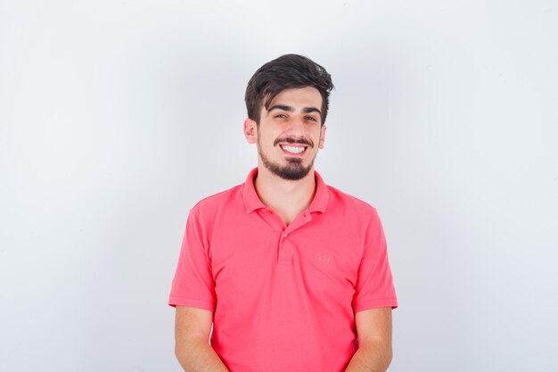 Young male in pink t-shirt looking and looking happy , front view.