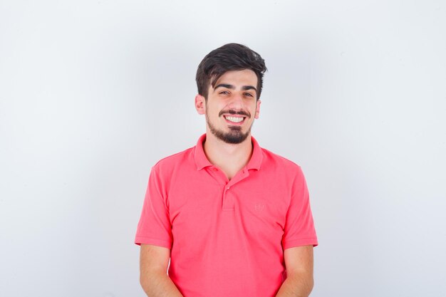 Молодой мужчина в розовой футболке смотрит и выглядит счастливым, вид спереди.