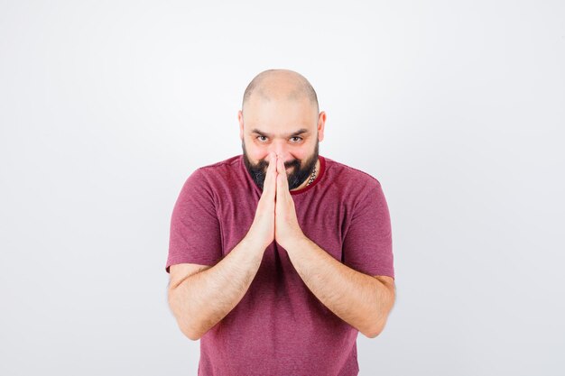 Young male in pink t-shirt showing namaste gesture , front view.