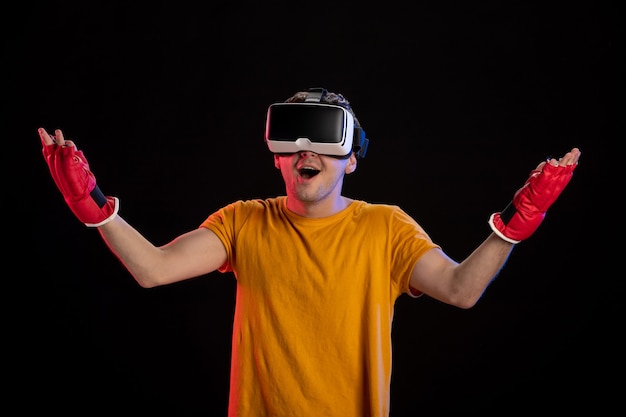 Young male playing virtual reality in mma gloves on dark surface