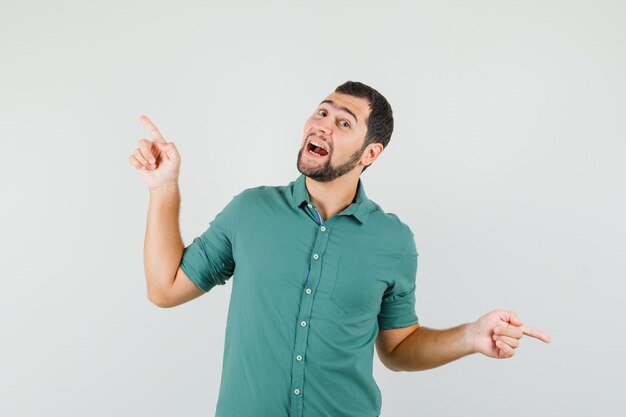 Young male pointing aside in green shirt and looking energetic. front view.