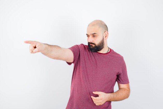 Young male pointing aside in t-shirt and looking confident. front view.