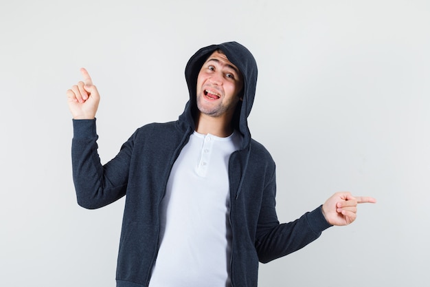 Free photo young male pointing away in t-shirt, jacket and looking cheerful. front view.