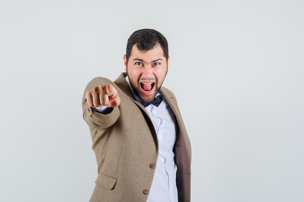 Free photo young male pointing at camera while screaming in suit front view.