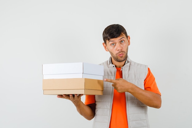 Free photo young male pointing at cardboard boxes in t-shirt