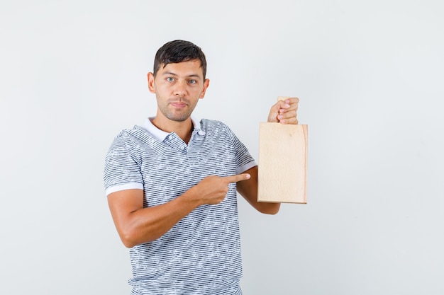 Young male pointing at cutting board in t-shirt and looking positive