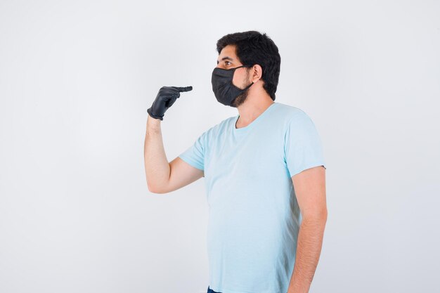 Young male pointing himself in t-shirt and looking focused , front view.