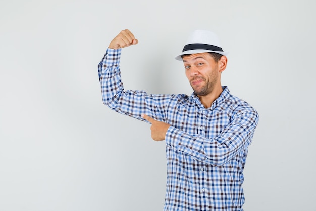 Free photo young male pointing at his arm muscles in checked shirt