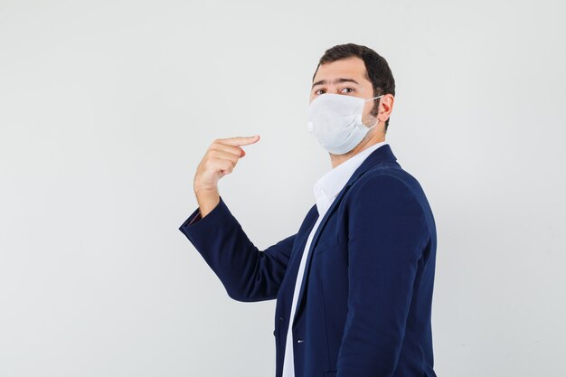 Young male pointing at his medical mask in shirt