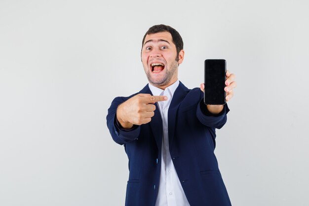 Young male pointing at mobile phone in shirt