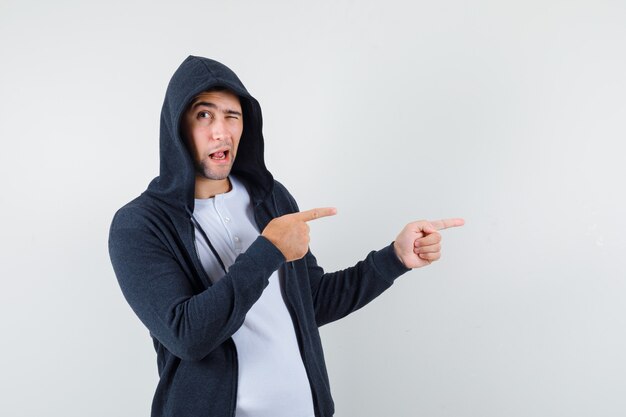 Young male pointing to the right side in t-shirt, jacket and looking confident , front view.