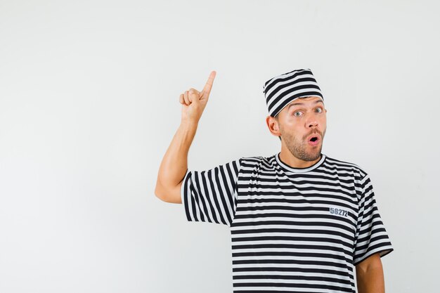 Young male pointing up in striped t-shirt hat and looking surprised