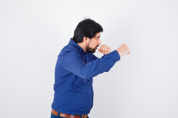 Free photo young male pretending to punch in shirt, jeans and looking furious. .