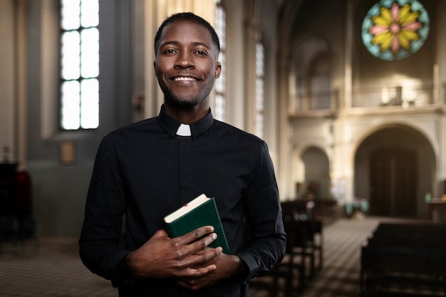 Giovane sacerdote maschio che tiene il libro sacro nella chiesa