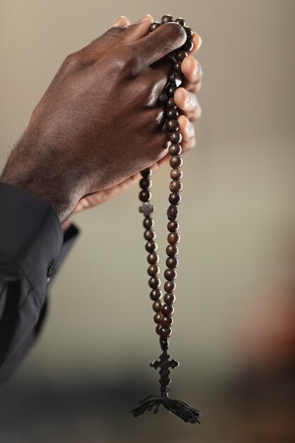 Young male priest praying in church with rosary