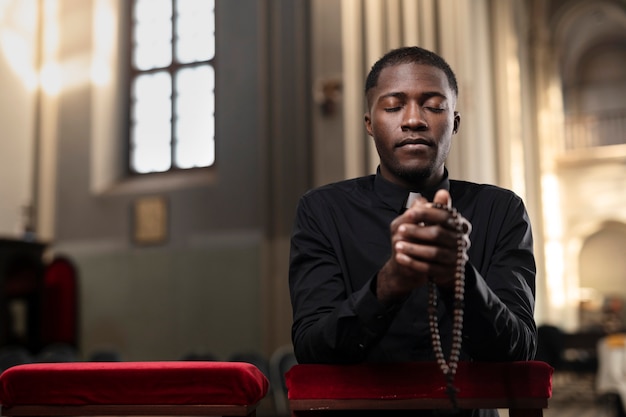 Бесплатное фото Молодой священник молится в церкви с четками
