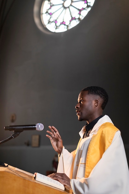 Молодой священник проповедует в церкви с помощью микрофона