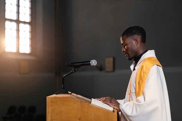 Young male priest preaching in the church using a microphone