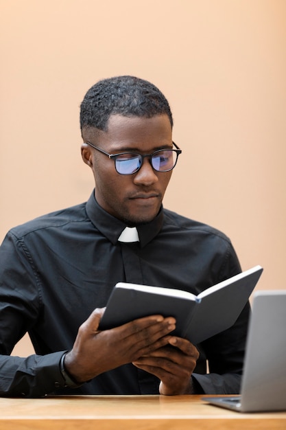 Young male priest reading a book at the cafe