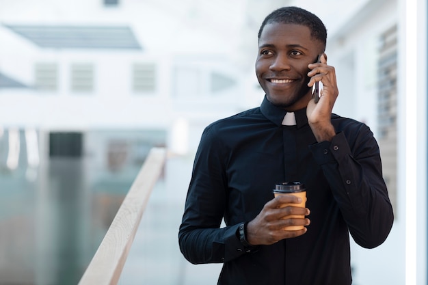Young male priest talking on smartphone