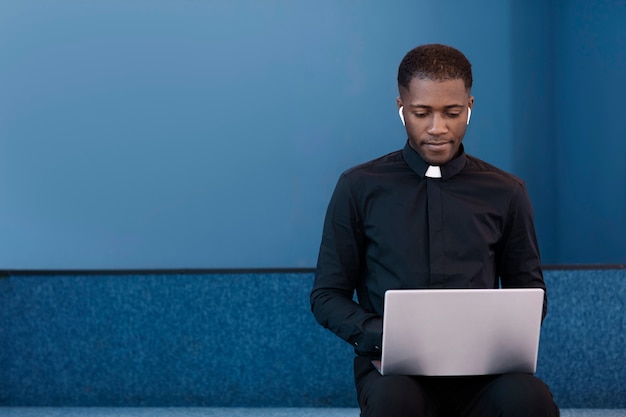 Young male priest using laptop