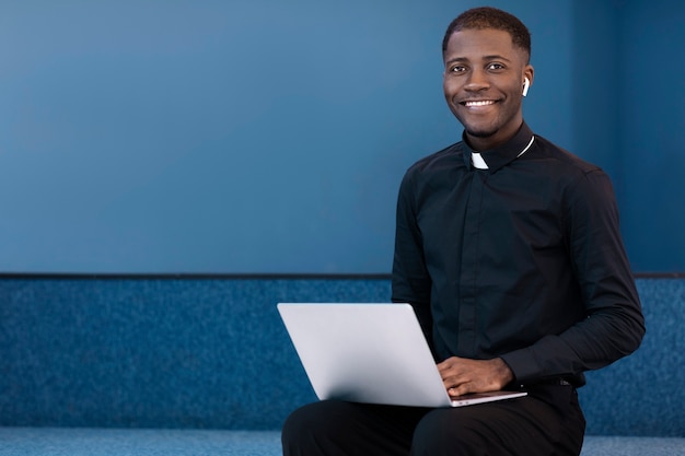 Young male priest using laptop