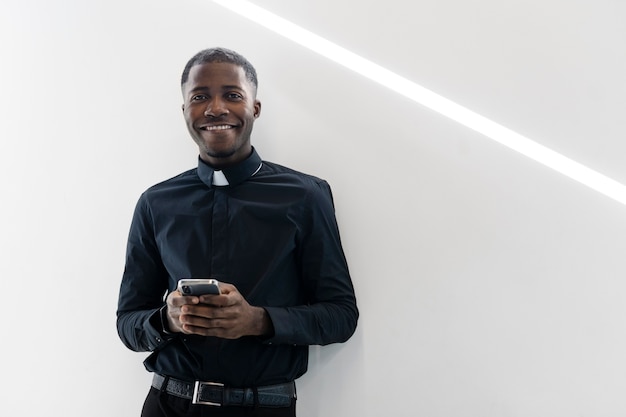 Young male priest using a modern smartphone