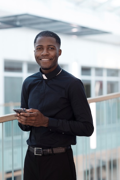 Young male priest using smartphone