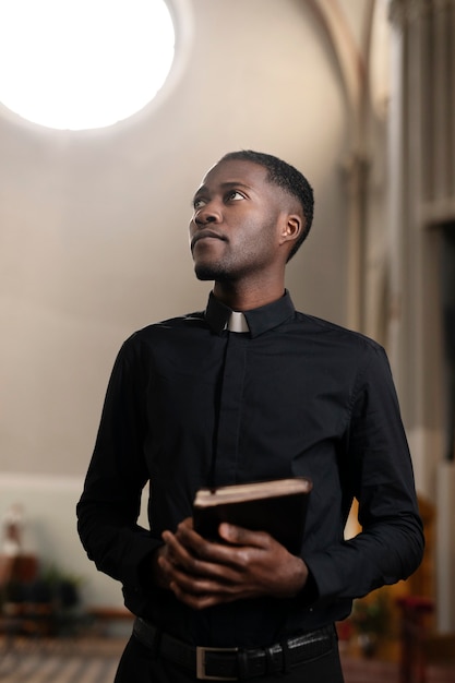 Free photo young male priest with a bible in church