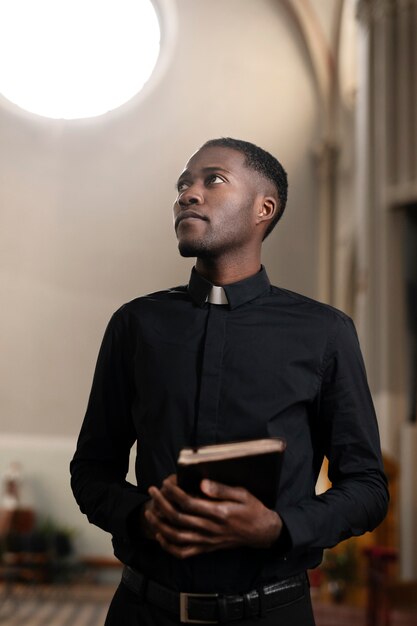 教会で聖書を持っている若い男性の司祭