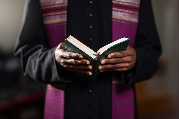 Молодой священник с библией в церкви