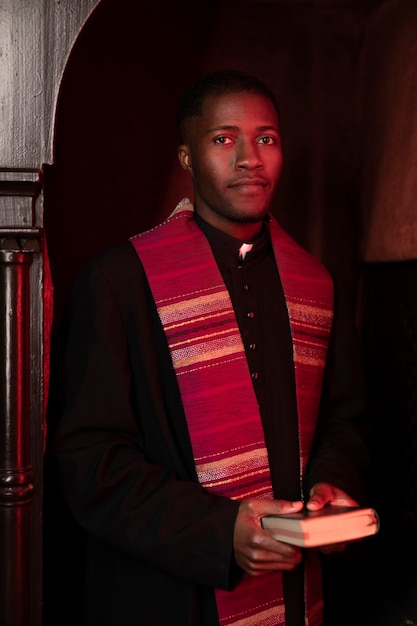 教会で聖書を持っている若い男性の司祭