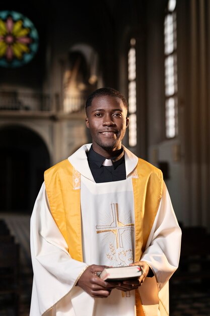 Young male priest with a bible in the church