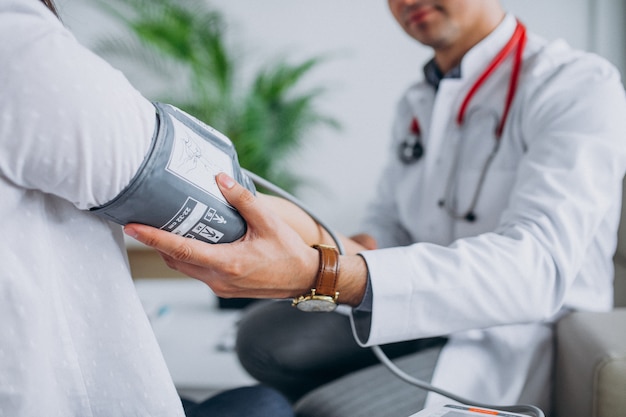 Young male psysician with patient measuring blood pressure