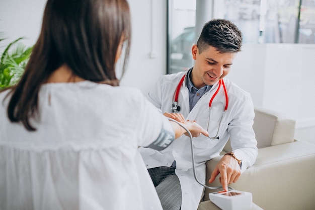 Young male psysician with patient measuring blood pressure