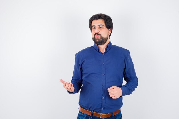 Young male in royal blue shirt discussing something and looking nervous , front view.