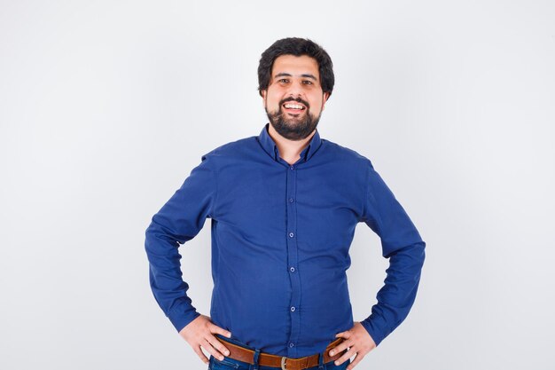 Young male in royal blue shirt smiling and looking weird , front view.