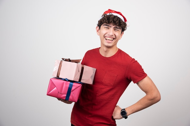 Молодой мужчина в шляпе Санта держит подарки