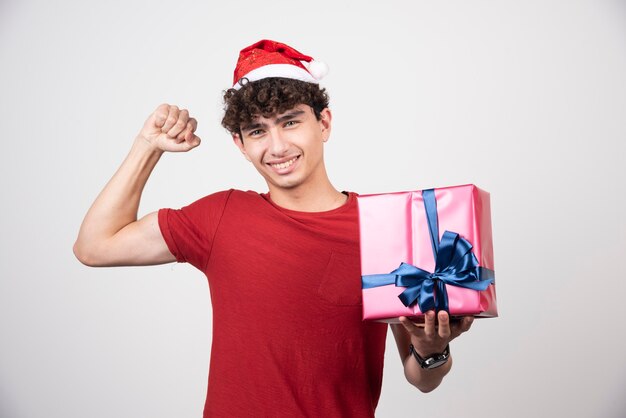 그의 근육을 보여주는 산타 모자에 젊은 남성.