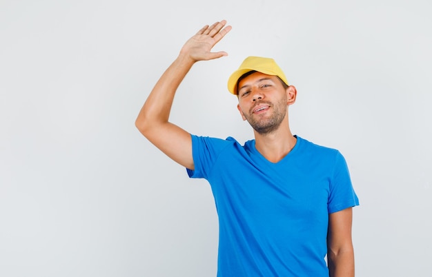 Young male saying goodbye with hand sign in blue t-shirt