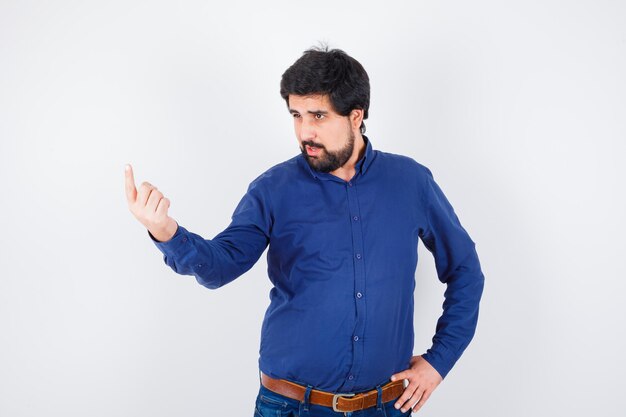 Young male in shirt, jeans pointing up and looking focused , front view.