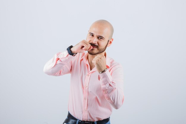 Young male in shirt, jeans standing in fight pose and looking confident , front view.