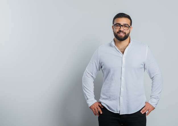 Young male in shirt, pants holding hands on waist and looking confident