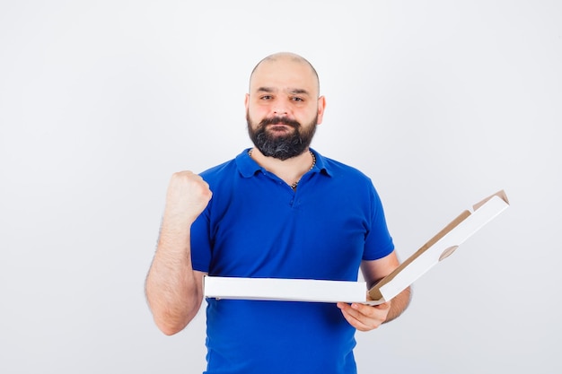 Free photo young male showing clnenched fist in t-shirt and looking confident , front view.