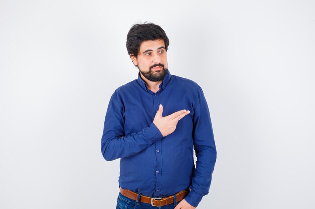 Young male showing gun gesture in shirt, jeans and looking pretty .