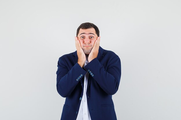 Young male showing hands on cheeks in shirt