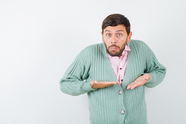 Free photo young male showing helpless gesture in shirt, cardigan and looking stressed , front view.