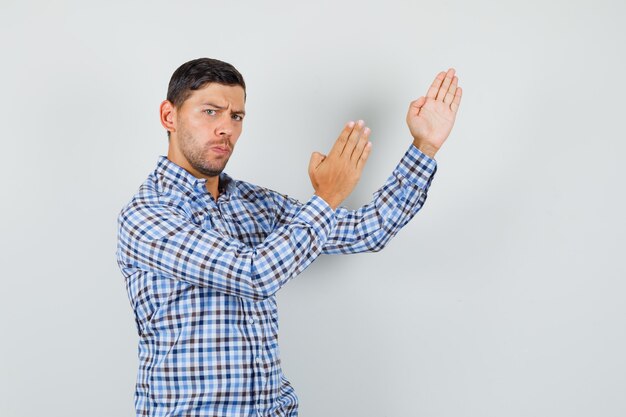 Young male showing karate chop gesture in checked shirt