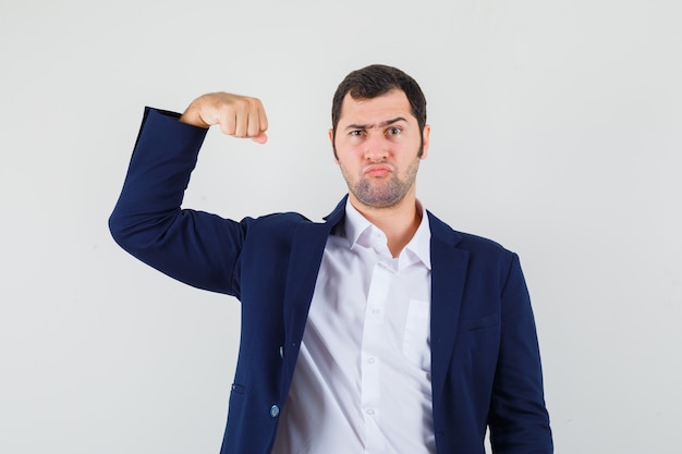 Young male showing muscles of arm in shirt, jacket and looking spiteful